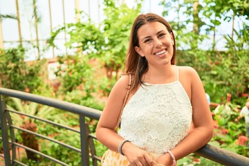 Young beatiful woman smiling happy and cheerful at butterfly garden on a sunny day of summer