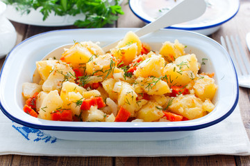 Baked sliced potatoes with carrots and onions in an enameled form, horizontal