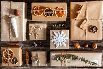 Creatively wrapped and decorated christmas presents in boxes on dark wooden background, flat lay, top view