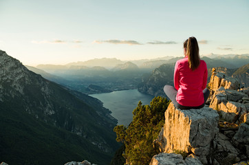 Naklejka premium Young woman sitting in front of a beautiful landscape, thinking and meditating at sunrise