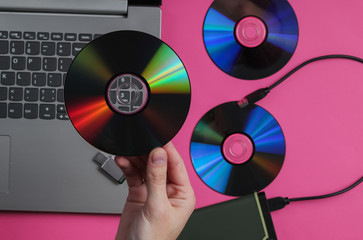 Female hand holds cd drives against the background of gadgets. Top view