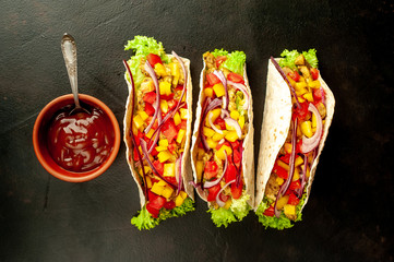 Mexican tacos with meat and vegetables on a stone background with copy space for your text.