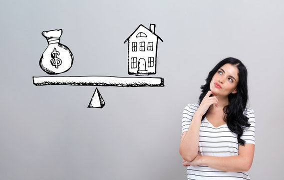 House And Money On The Scale With Young Woman In A Thoughtful Face