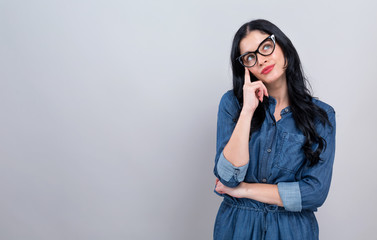 Young woman in a thoughtful pose on a gray background