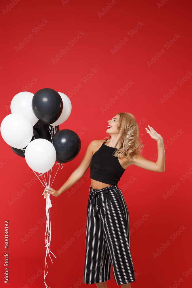 Wall mural cheerful young woman girl in black clothes posing isolated on red background. international women's 