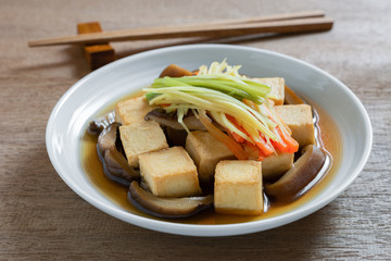 close up of steamed fish tofu with soy sauce in a ceramic dish on wooden table. asian homemade style food concept.
