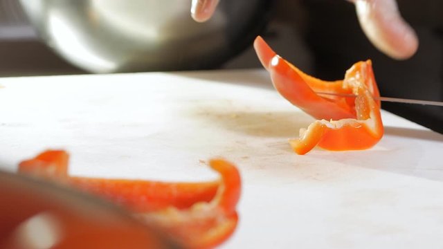 Male chef cutting fresh vegetable in slow motion. Closeup chef hands with knife slicing pepper at kitchen restaurant.