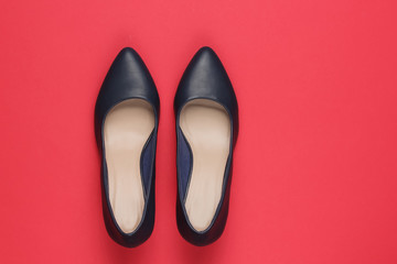 Classic women's high heel shoes on red paper background. Stylish shoes. Studio shot. Minimalistic fashion still life.