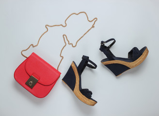 Minimalistic feshin still life. Sandals with platform, red leather bag on a white background. Top...