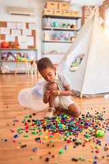 Beautiful african american toddler playing with small building blocks at kindergarten