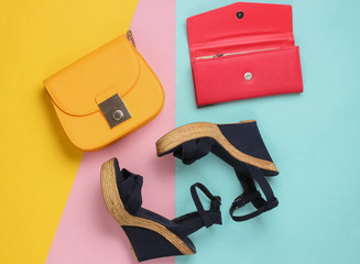 Minimalistic feshin still life. Sandals with platform, yellow leather bag, wallet on colored pastel...