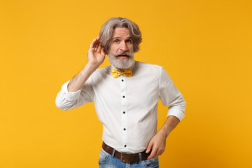 Elderly gray-haired mustache bearded man in white shirt bow tie posing isolated on yellow orange...