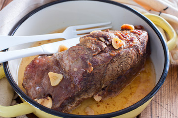 Baked beef fillet with pieces of garlic in a pan, horizontal