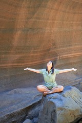 Young beauitufl hiker woman trekking natural orange mountain with arms raised celebrating summer holidays