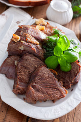 sliced baked beef fillet on a white dish with fresh herbs, selective focus