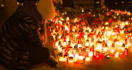 A young girl lights a candle on a religious of all saints day