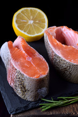 Raw red fish steaks on a slate board against black background