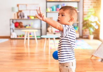 Beautiful toddler boy playing with colored small balls at kindergarten