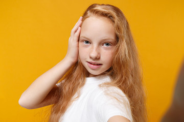 Close up of pretty little ginger kid girl 12-13 years old in white t-shirt isolated on yellow...