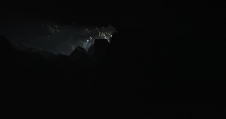 Reveal of two explorers entering a cave in slow motion with lights and smoke