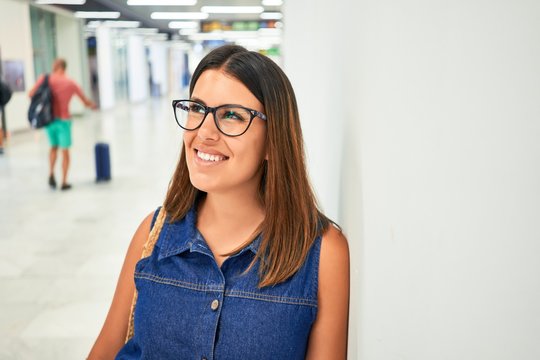 Young traveller woman at the airport going on vacation leaning on the wall