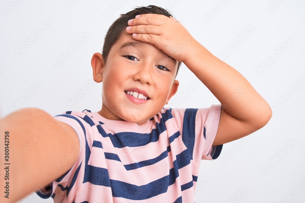 Canvas Prints Beautiful kid boy wearing casual striped t-shirt make selfie over isolated white background stressed with hand on head, shocked with shame and surprise face, angry and frustrated. Fear and upset