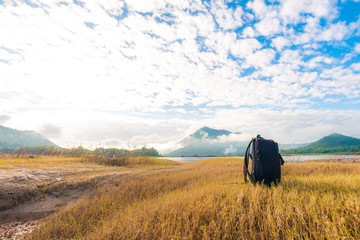 Black backpack on the yellow grass background with mountain view
