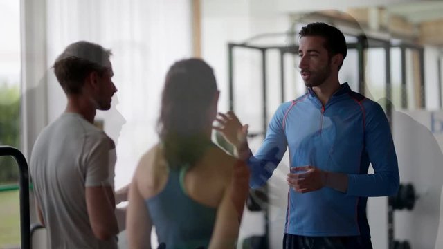 Gym instructor assisting two sports people 