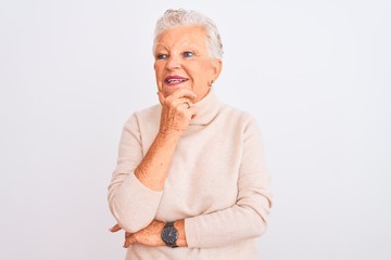 Senior grey-haired woman wearing turtleneck sweater standing over isolated white background with hand on chin thinking about question, pensive expression. Smiling and thoughtful face. Doubt concept.