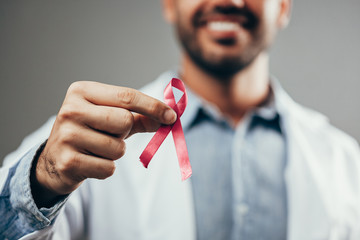 Red ribbon for HIV illness awareness in doctor's hand, 1 December World AIDS Day concept.