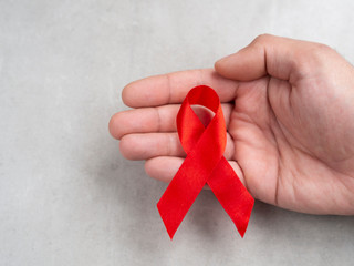 AIDS day ribbon in hand isolated on wall background. 1st December day concept