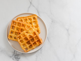 Delicious savory keto waffles. Two ingredients chaffles on plate over white marble background. Eggs...