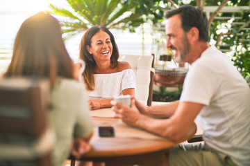 Beautiful family sitting on terrace drinking cup of coffee speaking and smiling