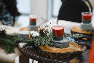 making Christmas decorations from red candles, Christmas tree branches and cones
