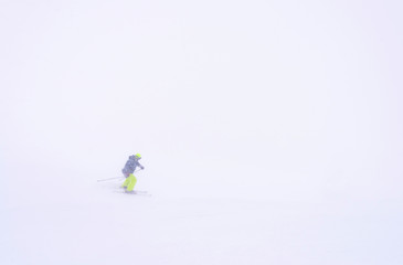 Skiers on a hillside in bad weather.