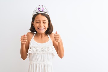 Beautiful child girl wearing princess crown standing over isolated white background excited for success with arms raised and eyes closed celebrating victory smiling. Winner concept. © Krakenimages.com