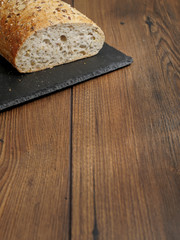 Fresh sourdough bread on a black slate plate on wooden table. Copy space.