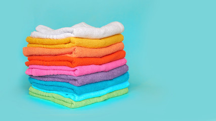 Fototapeta na wymiar stack of multi-colored clean towels on a blue background
