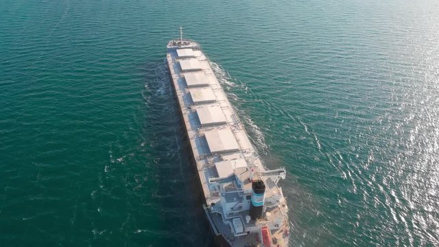 The large cargo vessel left the port after loading and moves in the right direction at high speed. Balker goes in the ocean.