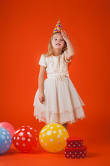 girl with gifts and balloons on an orange background. Studio portrait photos