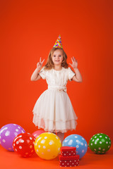 girl with gifts and balloons on an orange background. Studio portrait photos