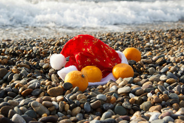 celebrating Christmas at sea. Santa Claus hat with tangerines on the beach