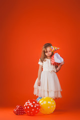 girl with gifts and balloons on an orange background. Studio portrait photos