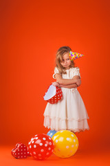 girl with gifts and balloons on an orange background. Studio portrait photos