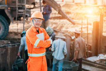 Asian engineer with hardhat using tablet inspecting and working at construction site