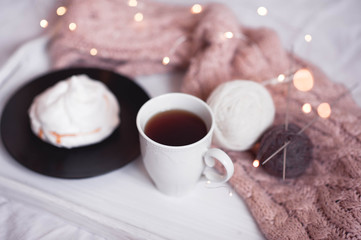 Mug of coffee with balls of yarn with knitted scarf on tray closeup. Autumn season. Christmas time. New Year.