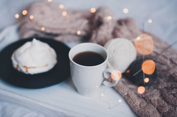 Cup of black tea with cake over glowing Christmas lights closeup. Good morning. Breakfast. New Year.