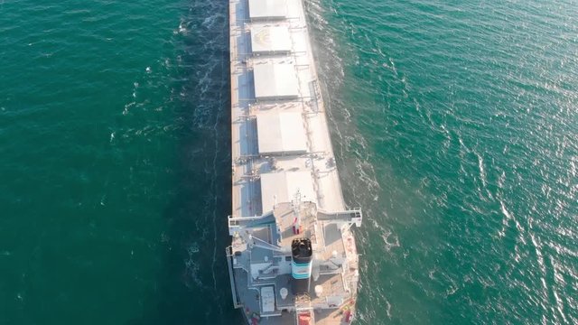 The large cargo vessel left the port after loading and moves in the right direction at high speed. Balker goes in the ocean.