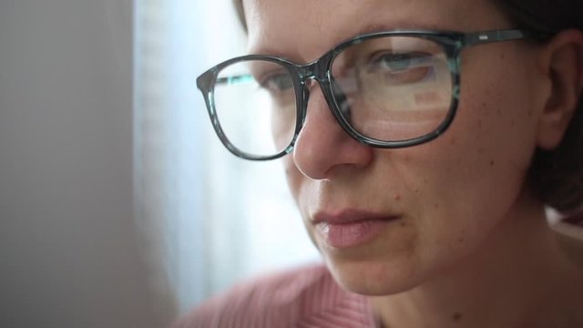 Closeup of a business woman with glasses looking at a laptop screen.