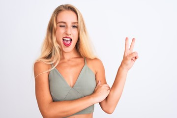 Young beautiful woman wearing casual green t-shirt standing over isolated white background smiling with happy face winking at the camera doing victory sign. Number two.